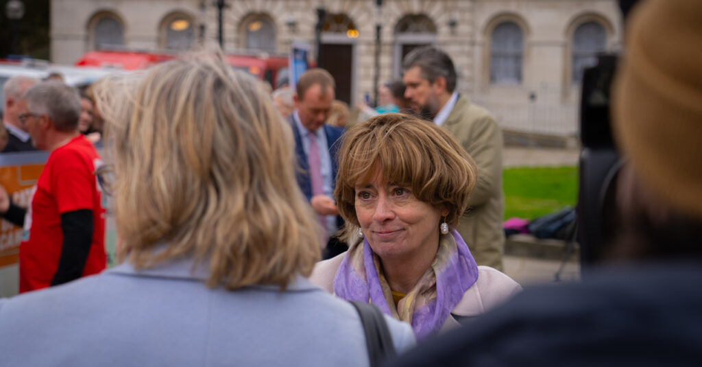 Professor Pat Price talking to people outside at event at Parliament.